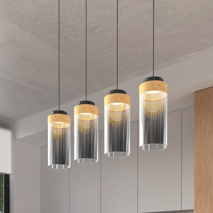 The Artika Hanson 4-light LED pendant with cylindrical glass shades and wooden accents hangs in a contemporary room with light gray walls and wood paneling.