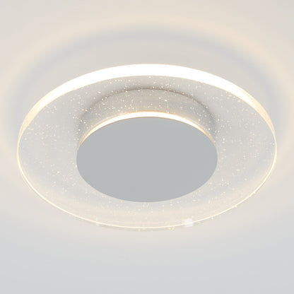 The Essence Disk LED flush mount by Artika-CAN-dev features a chrome finish, a central disc, and a clear ring with sparkling particles, emitting soft white light through an elegant glass diffuser.