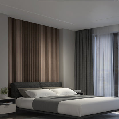 A modern bedroom features a dark upholstered bed, white and gray bedding, gray curtains, a large window, and a bedside table with a potted plant. The wooden slatted accent wall uses the Artika Panolok 30.67 ft wall panel kit (pack of 8).