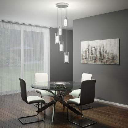 Modern dining room with a round glass table, four white and gray chairs, the Artika Hologram 5-light LED pendant, gray walls, abstract cityscape artwork, wooden floors, and large window with sheer curtains overlooking a garden.
