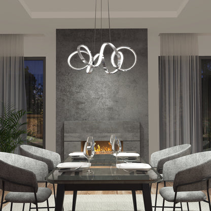 A modern dining room features a glass table for four, gray upholstered chairs, a contemporary fireplace, large windows with sheer curtains, and an Artika-CAN-dev Swirl Ribbon LED pendant light overhead.