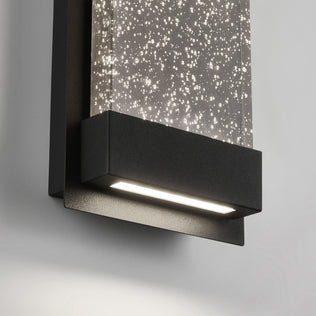 Close-up of the Artika Essence Glow Box indoor-outdoor LED wall light, featuring a black frame and a rectangular panel with tiny illuminated bubbles that create a sparkling effect against a white background.