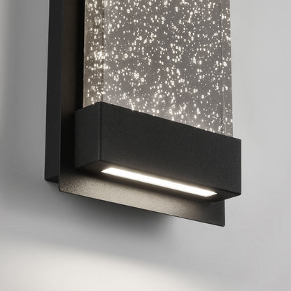 Close-up of the Artika Essence Glow Box indoor-outdoor LED wall light, featuring a black frame and a rectangular panel with tiny illuminated bubbles that create a sparkling effect against a white background.