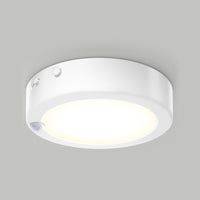 Artika Accent under cabinet LED light 3CCT with a glowing center and small sensor on the edge, mounted on a plain gray ceiling.