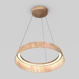 A modern, circular pendant light fixture made of wood hangs from the ceiling by three thin wires. The light is suspended and has an inner ring that emits a soft glow. The background is plain gray.