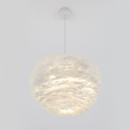 The Artika Plume LED pendant light, featuring a round, feather-like white design and textured layers, hangs from a thin cord and emits a soft, diffused glow against a plain white background.