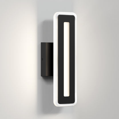 The Artika Evasion modern indoor-outdoor LED wall light 3 CCT is a black and white rectangular sconce with a central cutout, mounted vertically on a light gray wall and casting soft edge lighting.