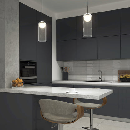 Modern kitchen with dark cabinets, white countertops, a gray barstool, bowl of oranges, cup on the counter, subway tile backsplash, built-in appliances, and two Artika Mirah LED modern mid-century pendant lights overhead.