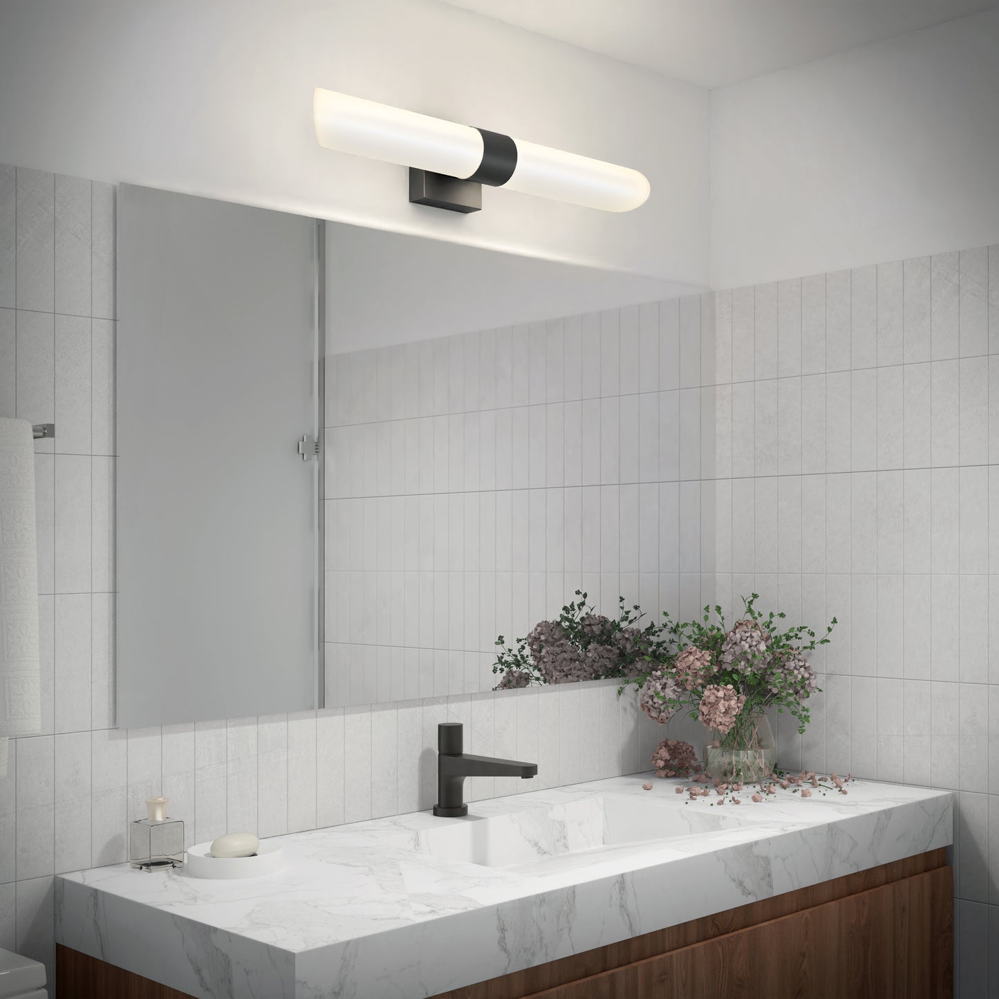 Modern bathroom with a large mirror, marble countertop, black faucet, and vase of flowers. Above the mirror is the Artika Wilton LED modern bathroom vanity light 5 CCT with a frosted glass shade and black accents.