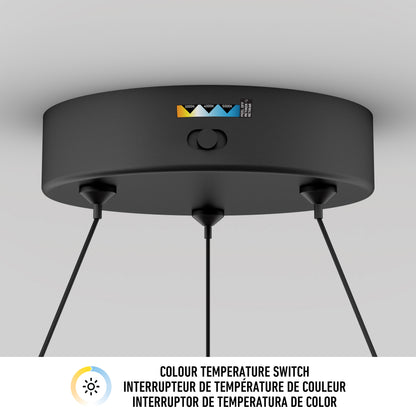 Close-up of a black ceiling light fixture with a color temperature switch labeled in English, French, and Spanish. Three cords hang from the fixture, and a color temperature chart is visible on its surface.