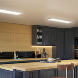 Modern kitchen with dark cabinets, light wood countertops, built-in stove, and overhead rectangular ceiling lights. Shelves display white dishes, and a chair is placed at the kitchen island.