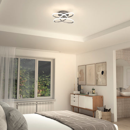 A modern bedroom features the Artika Swirl Butterfly LED contemporary flush mount light, a large window with sheer curtains, a wooden sideboard with decor, neutral bedding, abstract wall art, and an open doorway to the bathroom.