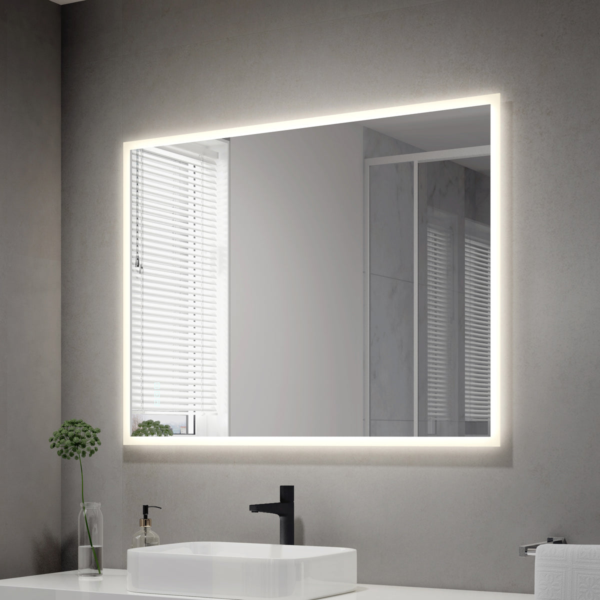 A modern bathroom features the Artika Mavis 48" x 36" Rectangular LED Mirror with defogger on a gray wall, paired with a white sink and black faucet, a small green plant in a glass vase, and a window with white blinds.