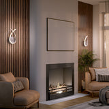Modern living room with neutral-toned armchairs, a black fireplace, a plant, and wall art above the mantel. Vertical wood paneling and sleek sconces flank the fireplace, with large windows letting in natural light.