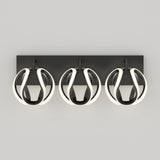 A modern wall-mounted light fixture with three spherical LED lights, each encased in a black and white looped design, set against a rectangular black base on a light gray background.