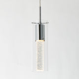 A modern pendant light with a cylindrical clear glass shade and chrome fixture, featuring a bubble-filled illuminated center, hangs against a plain white background.