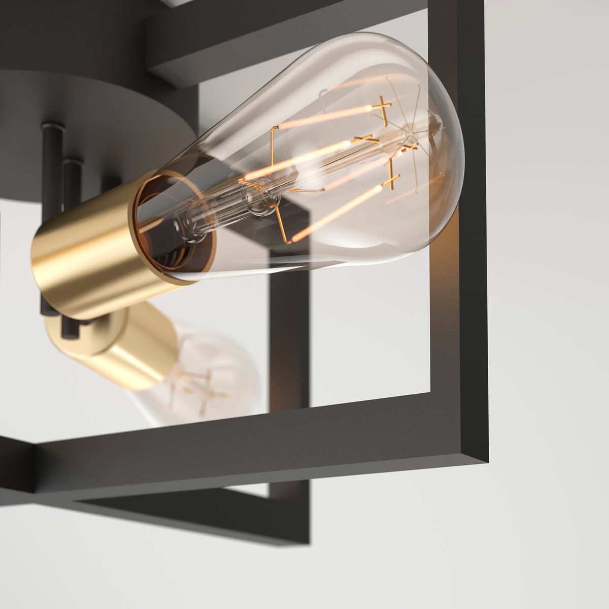 A close-up of a modern light fixture featuring an exposed Edison-style bulb with visible filaments, held in a gold socket and surrounded by a black geometric metal frame against a white background.