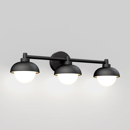 The Artika Boden LED mid-century bathroom vanity light 5 CCT is a modern black wall-mounted fixture with three dome-shaped shades, each featuring a round glowing bulb, shown against a plain light gray background.
