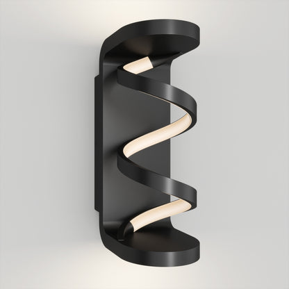 The Artika Swirl indoor-outdoor LED wall light features a black frame and spiral-shaped LED strip, mounted vertically on a white wall. Its sleek, modern design emits soft, diffused light for contemporary spaces.