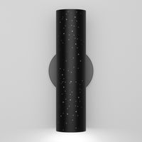 The Artika Cosmic indoor-outdoor LED wall light 3 CCT features a modern black cylindrical design with star-like perforations on a circular base, casting downward light against a plain white wall.