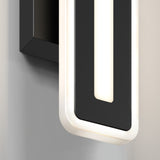 Close-up of a modern wall light fixture with a rectangular black frame and rounded corners, featuring a glowing white LED strip outlining its shape, mounted on a light-colored wall.