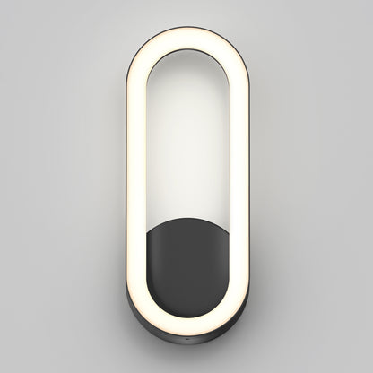 The Artika Aiden modern LED indoor-outdoor wall light 5 CCT features an oval LED with a black half-oval base, mounted on a light gray wall and emitting a soft, even glow.
