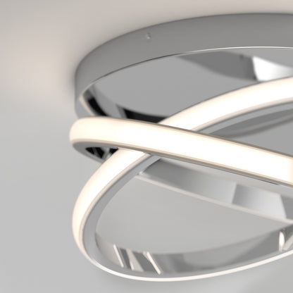 The Artika Orbia modern LED flush mount light 3 CCT features intertwined glowing rings and a metallic circular base, elegantly mounted on a white ceiling.