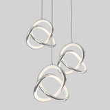 Three modern pendant lights with intertwined chrome and glowing white loops hang against a plain light gray background.