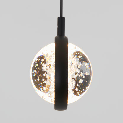 The Artika Avalon LED 1-light pendant features a modern round clear glass shade with inner bubbles and a black central fixture, suspended against a plain light gray background.