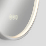 A close-up of a round, illuminated mirror with a soft LED light around its edge and blurred digital numbers reflected on its surface. The background is plain and light-colored.