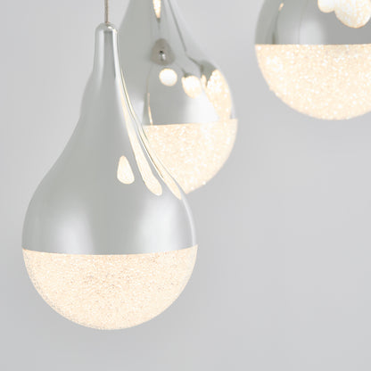 Close-up of three Artika Glitzer 5-light LED pendants with teardrop shapes, shiny metallic tops, and textured glowing white bottoms, set against a plain light gray background.