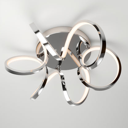 The Artika Swirl Ribbon LED flush mount light features curving chrome-finished strips looping around a circular base; this dimmable fixture casts soft light and artistic shadows on any white ceiling.