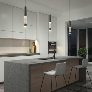 Modern kitchen with a gray stone island, two bar stools, built-in cabinets, a built-in oven, a sink with a black faucet, a plant near large windows, and Mist LED pendant lights by Artika hanging above.
