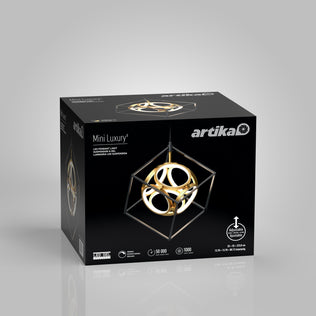 The Artika Mini Luxury LED pendant light comes in a black box displaying the modern geometric fixture, which features gold rings within a black cube frame, along with product details on the packaging.