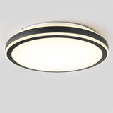 A modern circular ceiling light with a black outer ring and a glowing white center, mounted on a plain grey ceiling.