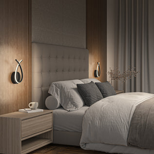 Modern bedroom with a tufted headboard, neutral bedding, two gray accent pillows, wooden nightstands (one with a cup), floor-length curtains, soft lighting, a vase with branches, and Artika Gamma modern LED wall sconce 5 CCT on the wall.
