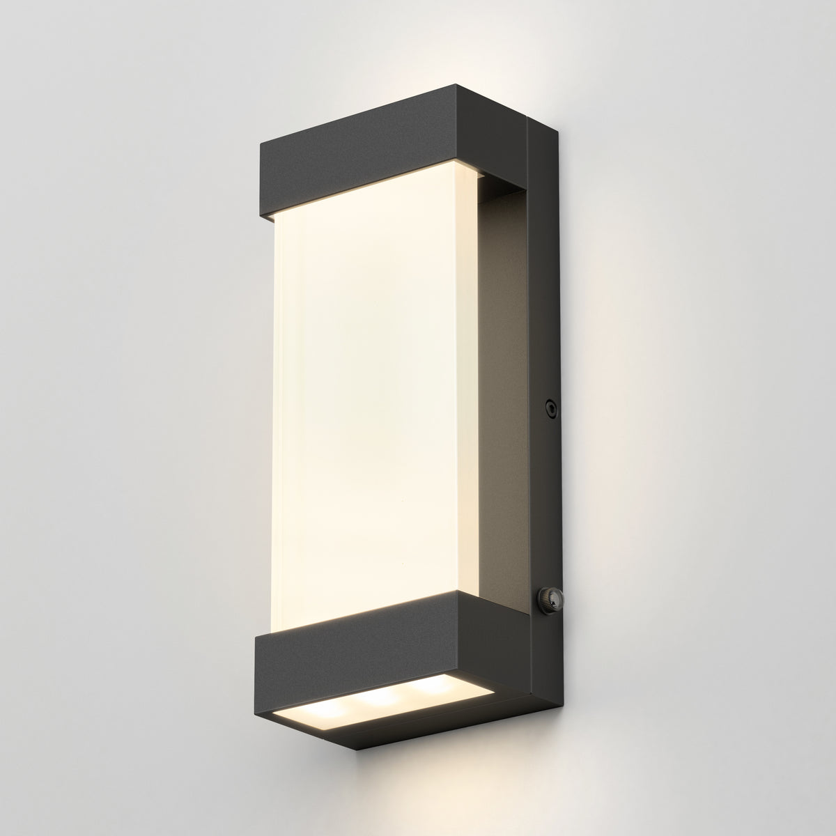 The Artika Glacier indoor-outdoor LED wall light features a matte black frame and frosted white diffuser, mounted on a light gray wall, casting soft up-and-down lighting with its modern rectangular design.