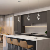 A modern kitchen with dark cabinets, a white marble island with three beige barstools, pendant spiral lights above, and a cup and saucer on the counter. Large windows with sheer curtains let in natural light.