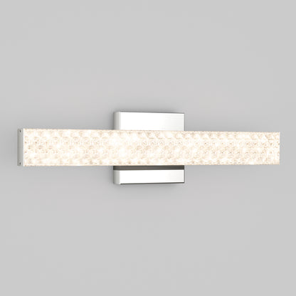 The Artika Adeline modern LED bathroom vanity light 3 CCT features a rectangular, textured, illuminated glass bar and a sleek metallic base, shown wall-mounted against a plain light gray background.