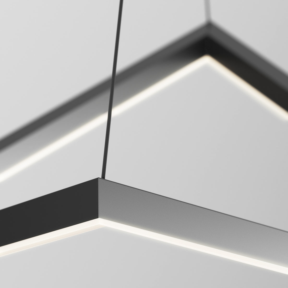 Close-up of a modern, black, rectangular pendant light fixture with integrated LED strips suspended from the ceiling by thin cables against a plain, light-colored background.
