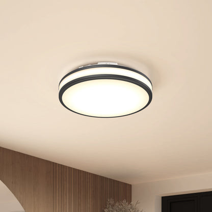 The Artika Hemisphere 15 in. LED flush mount light, featuring 5 CCT adjustable brightness and a black trim, casts diffused white light on a beige ceiling above wood paneling and a white archway.