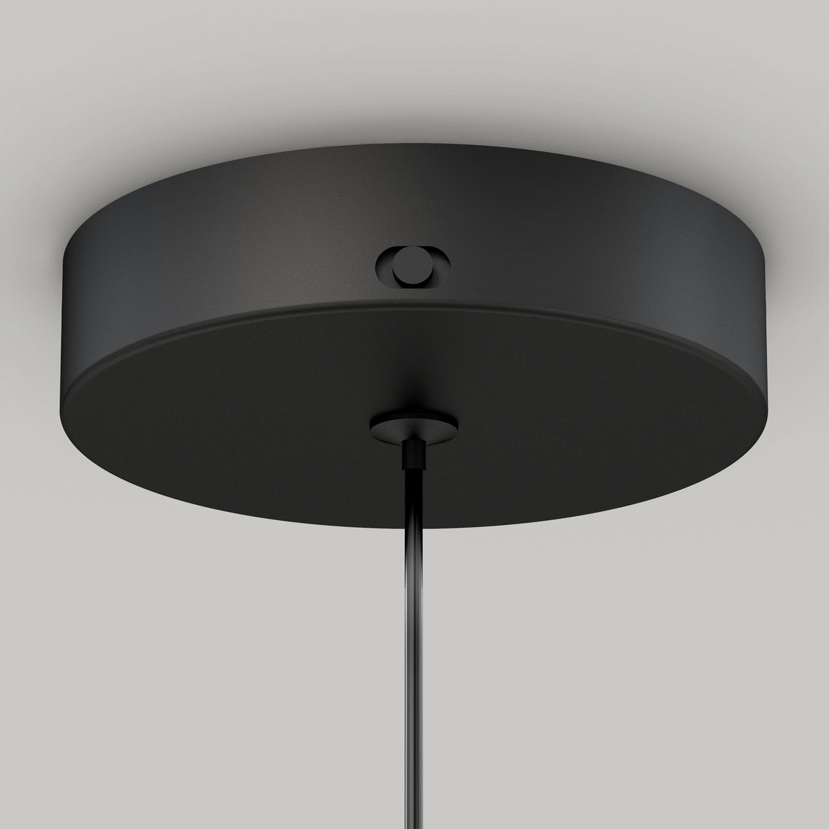 A close-up view of a modern, round black ceiling light canopy with a cord hanging down from its center, set against a plain white ceiling.
