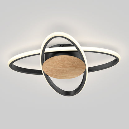 The Artika Atomic 15 in. LED flush mount light features a circular wooden center and two intersecting black metal rings with integrated LEDs, creating an abstract, planetary-inspired look against a light gray background. 5 CCT selectable.