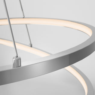 Close-up of the Salto LED pendant light by Artika, featuring a modern circular design with a chrome finish and soft diffused white light, suspended by thin cables against a plain background—ideal for contemporary interiors.