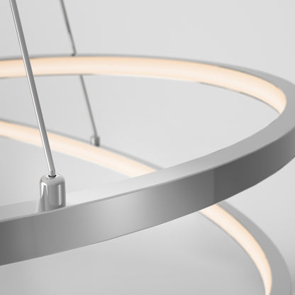 Close-up of the Salto LED pendant light by Artika, featuring a modern circular design with a chrome finish and soft diffused white light, suspended by thin cables against a plain background—ideal for contemporary interiors.