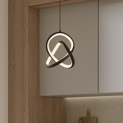 The Artika Zephyr LED pendant, featuring a modern abstract looped design, hangs in a kitchen with wood accents, beige cabinets, and a speckled backsplash.