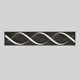 A modern wall light fixture with two intertwined, wave-like LED tubes mounted on a rectangular black base, set against a plain light gray background.