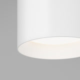Close-up of a modern, cylindrical white ceiling light fixture with a smooth texture, softly illuminating the area below against a plain gray background.