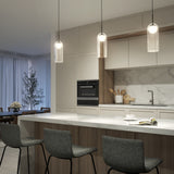 Modern kitchen with a marble island, three gray stools, hanging pendant lights, built-in oven, white cabinets, and a sink. Dining area with a table and large window with sheer curtains in the background.