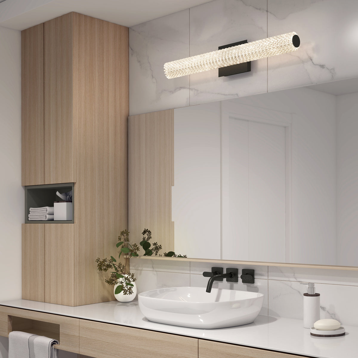 Modern bathroom with a round white vessel sink, black faucet, light wood cabinetry, a large mirror, glass light fixture above, and small plant on the counter. White and marble surfaces create a clean, minimalist look.